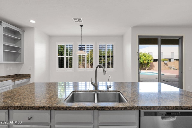 kitchen with open shelves, stainless steel dishwasher, a kitchen island with sink, a sink, and dark stone countertops