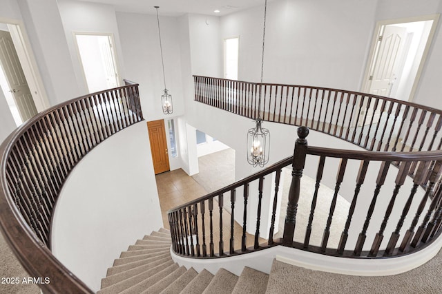 stairs featuring a high ceiling, recessed lighting, and a notable chandelier