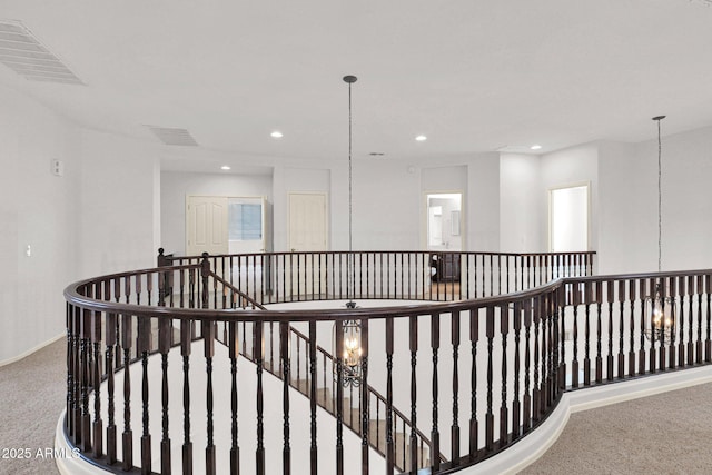 corridor with carpet floors, visible vents, a notable chandelier, and an upstairs landing