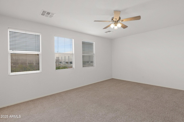 carpeted empty room featuring a ceiling fan and visible vents