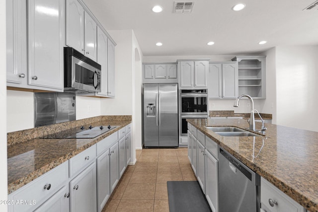 kitchen featuring light tile patterned flooring, stainless steel appliances, a sink, visible vents, and open shelves