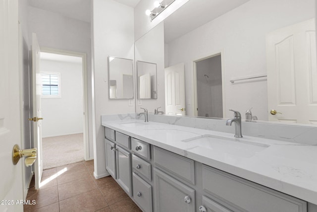 bathroom featuring double vanity, tile patterned flooring, a sink, and baseboards