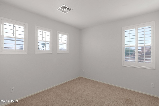 spare room featuring carpet, visible vents, and baseboards