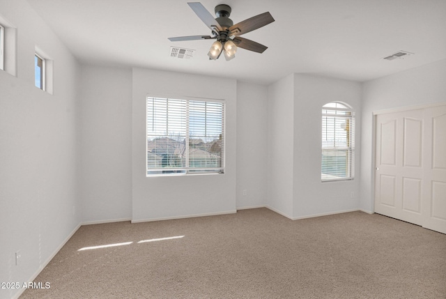 spare room with light carpet, a wealth of natural light, and visible vents