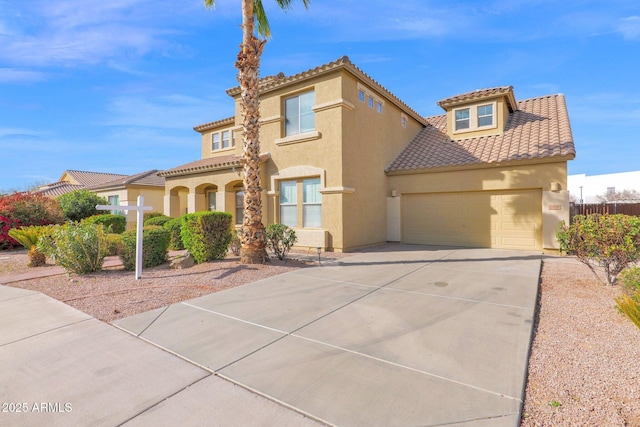 mediterranean / spanish home featuring an attached garage, fence, a tile roof, concrete driveway, and stucco siding