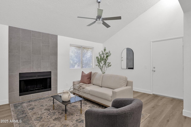 1075 E Chandler Blvd Unit 212, Chandler, AZ 85225 - living room with light wood-type flooring, a textured ceiling, a ceiling fan, a tiled fireplace, and high vaulted ceiling