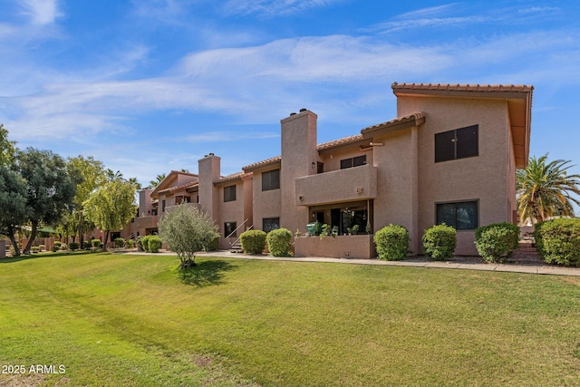 1075 E Chandler Blvd Unit 212, Chandler, AZ 85225 - back of property featuring stucco siding, a lawn, a tile roof, and a chimney