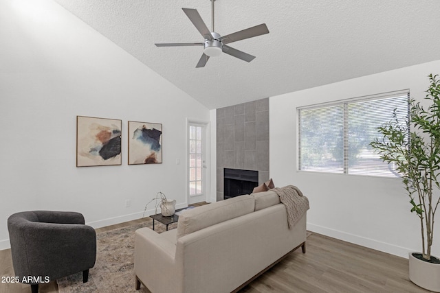 1075 E Chandler Blvd Unit 212, Chandler, AZ 85225 - living room featuring ceiling fan, wood finished floors, a tile fireplace, a textured ceiling, and high vaulted ceiling