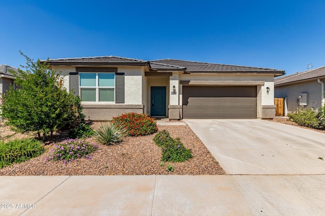 prairie-style house featuring a garage, stucco siding, driveway, and a tiled roof