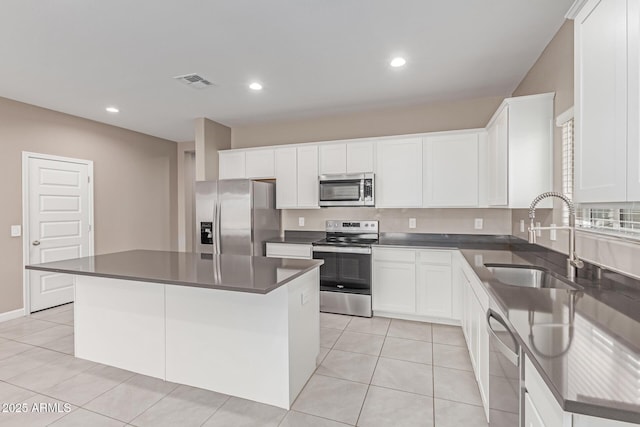 kitchen with white cabinets, a sink, a center island, stainless steel appliances, and visible vents