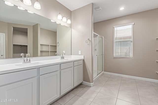 bathroom featuring a sink, tile patterned flooring, double vanity, baseboards, and a stall shower