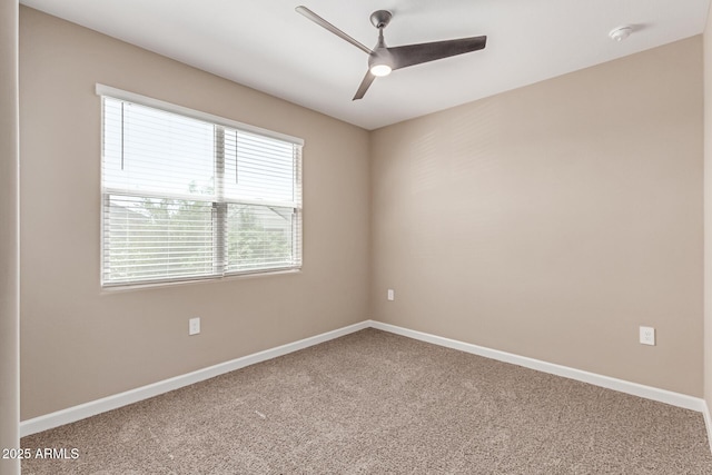 empty room with carpet floors, a ceiling fan, and baseboards