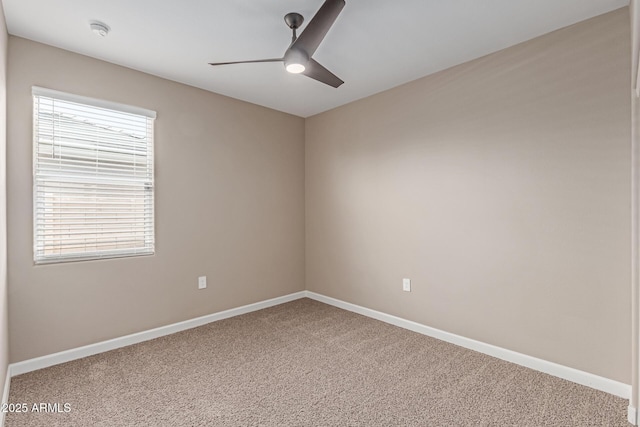 carpeted spare room with a ceiling fan and baseboards