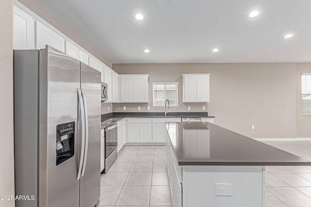 kitchen with stainless steel appliances, dark countertops, light tile patterned floors, and a sink