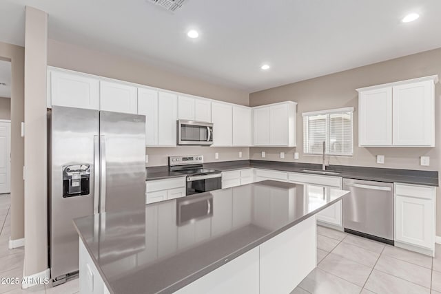 kitchen featuring visible vents, dark countertops, white cabinets, a sink, and stainless steel appliances