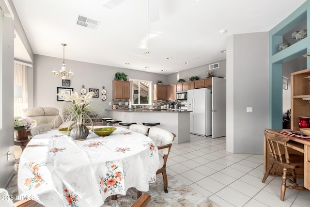 tiled dining space with a healthy amount of sunlight and a notable chandelier