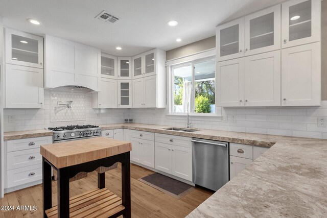 kitchen featuring decorative backsplash, white cabinetry, stainless steel appliances, light wood-type flooring, and sink