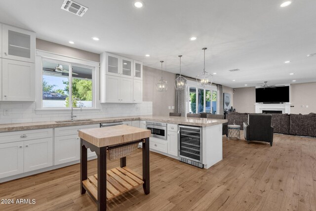 kitchen featuring wine cooler, white cabinetry, and a healthy amount of sunlight