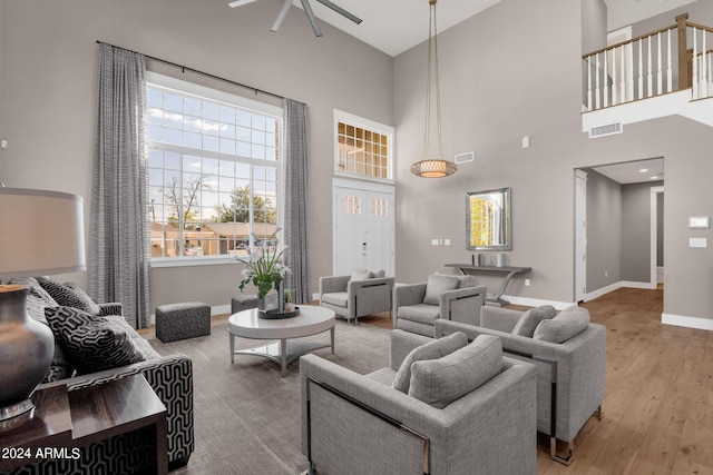 living room featuring light wood-type flooring, a high ceiling, ceiling fan, and a wealth of natural light