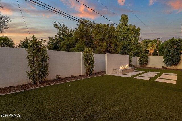 patio terrace at dusk with a lawn and a fire pit