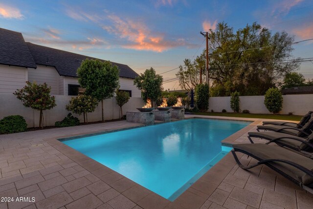 back house at dusk featuring a patio area and a yard