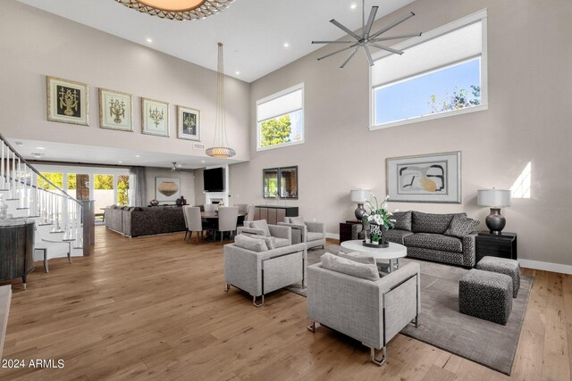 living room featuring light hardwood / wood-style floors, a towering ceiling, ceiling fan, and plenty of natural light