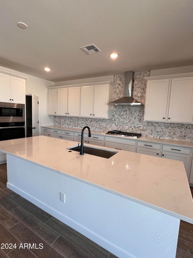 kitchen with white cabinets, sink, wall chimney range hood, backsplash, and stainless steel appliances