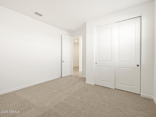 unfurnished bedroom with a closet and light colored carpet