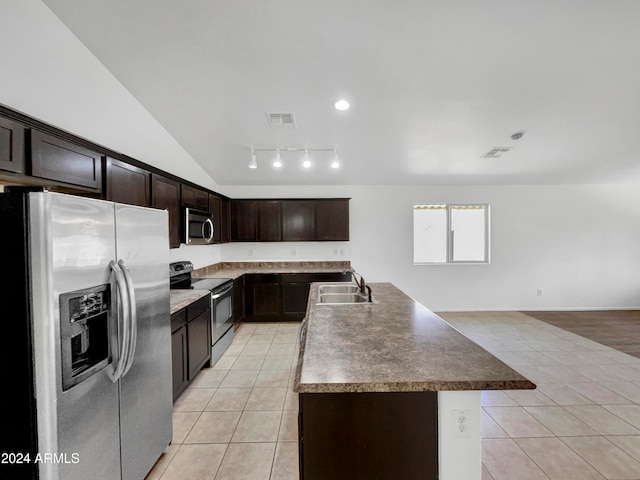 kitchen featuring dark brown cabinetry, sink, vaulted ceiling, a center island with sink, and appliances with stainless steel finishes