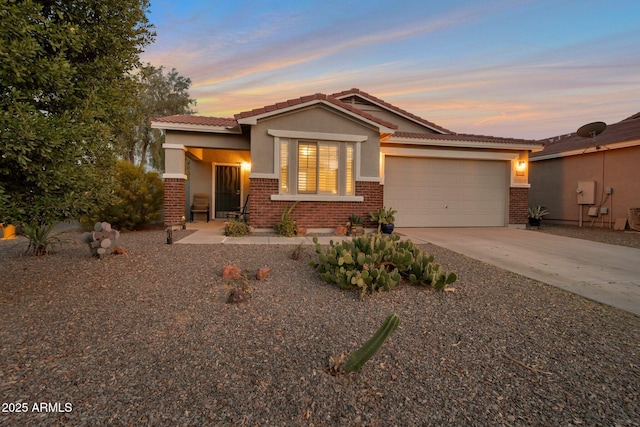 view of front of home featuring driveway, stucco siding, a tile roof, an attached garage, and brick siding