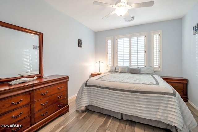 bedroom featuring ceiling fan, wood finished floors, visible vents, and baseboards