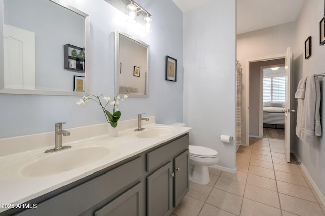 full bath featuring toilet, tile patterned flooring, double vanity, and a sink