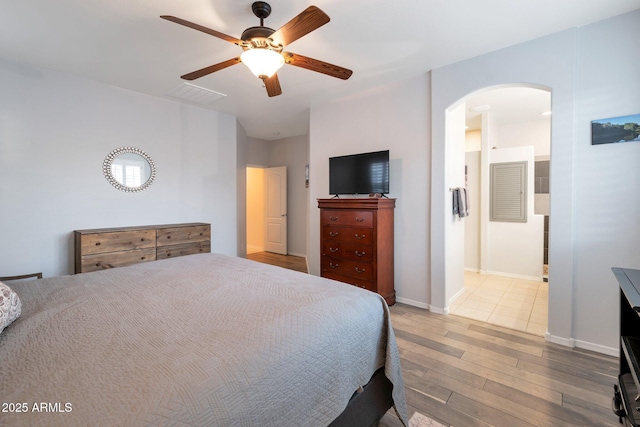 bedroom featuring baseboards, visible vents, a ceiling fan, arched walkways, and wood finished floors