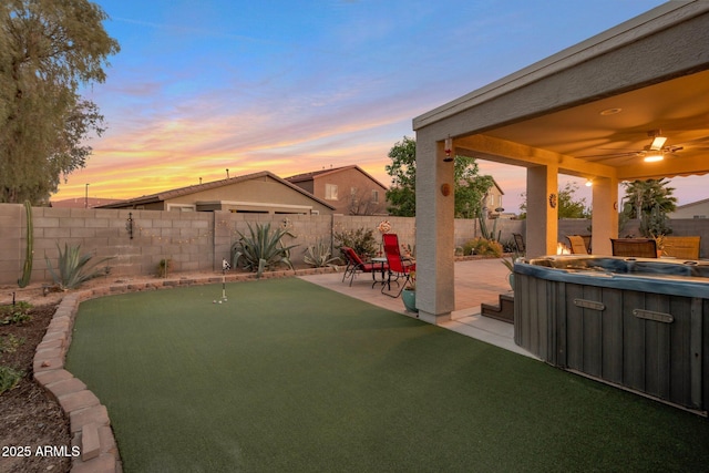 yard at dusk with a patio, a fenced backyard, and a ceiling fan