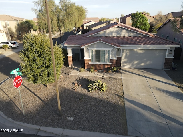 view of front of property featuring driveway, a tiled roof, an attached garage, and brick siding