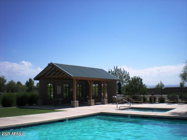 pool with an outbuilding, fence, a hot tub, and a patio