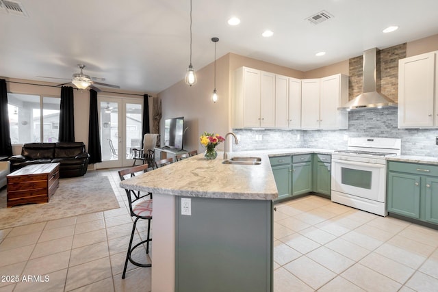 kitchen with wall chimney range hood, white gas range oven, visible vents, and a sink