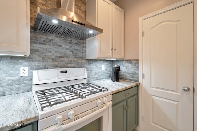 kitchen featuring wall chimney range hood, white range with gas cooktop, light stone counters, and backsplash