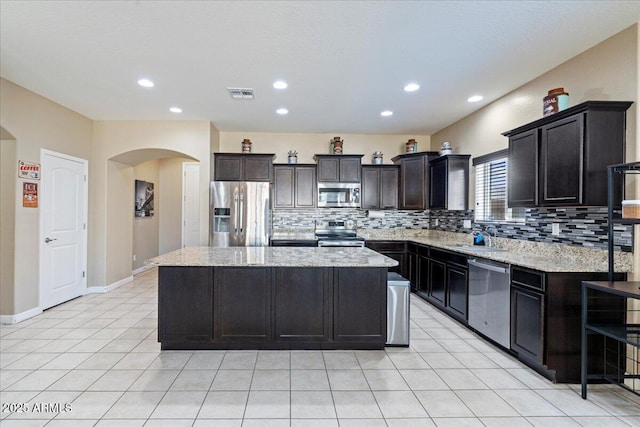 kitchen with visible vents, a kitchen island, a sink, decorative backsplash, and appliances with stainless steel finishes