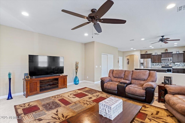 living room with visible vents, baseboards, recessed lighting, arched walkways, and light carpet