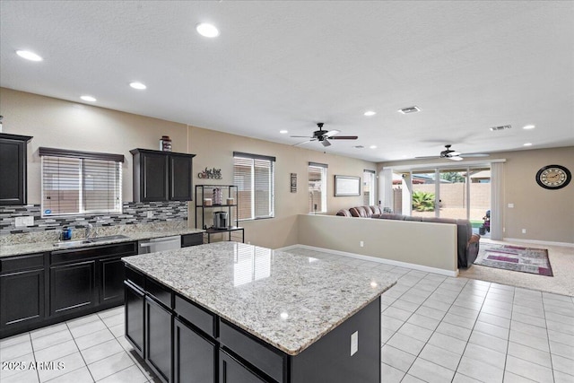 kitchen with light tile patterned flooring, a sink, open floor plan, dishwasher, and tasteful backsplash