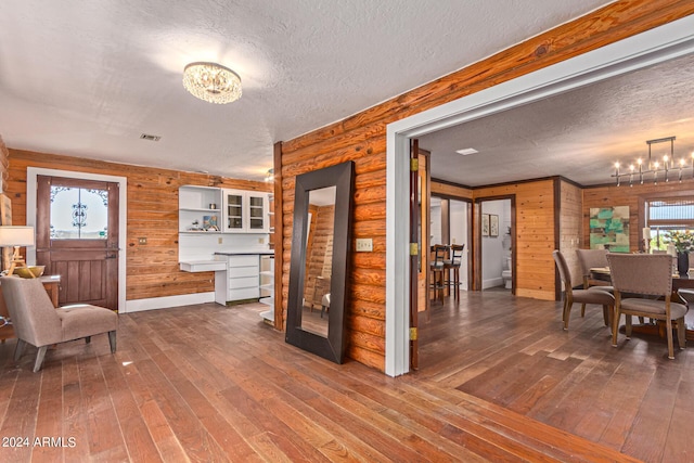 interior space featuring hardwood / wood-style floors, a textured ceiling, a notable chandelier, and wood walls