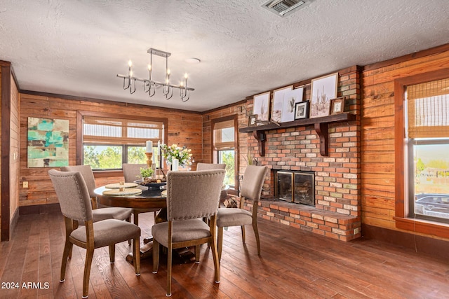 dining area with a brick fireplace, wooden walls, dark hardwood / wood-style floors, and a notable chandelier