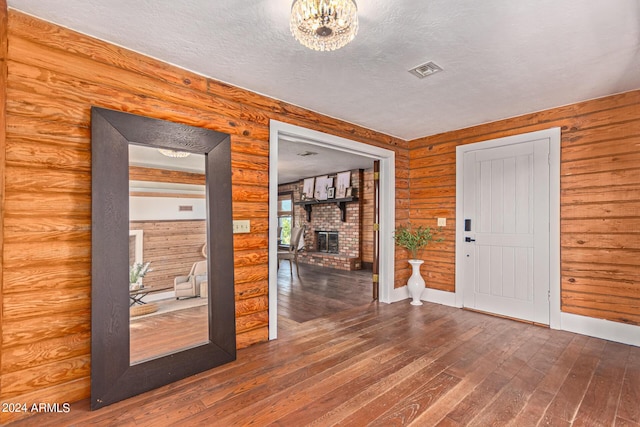 1060 S Kellis Rd, Wickenburg, AZ 85390 - foyer entrance featuring dark wood-style floors, a brick fireplace, a textured ceiling, and a chandelier