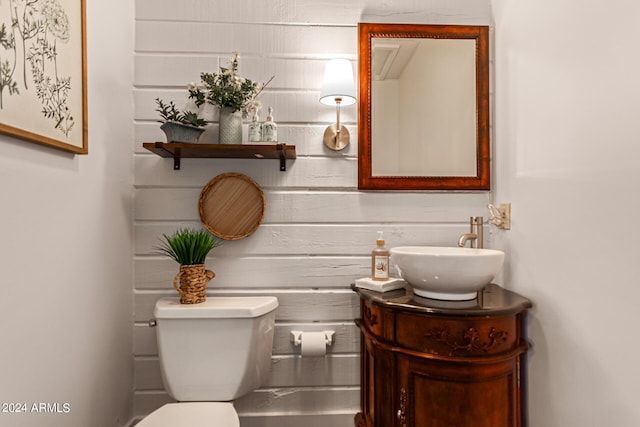 bathroom featuring vanity, toilet, and wooden walls