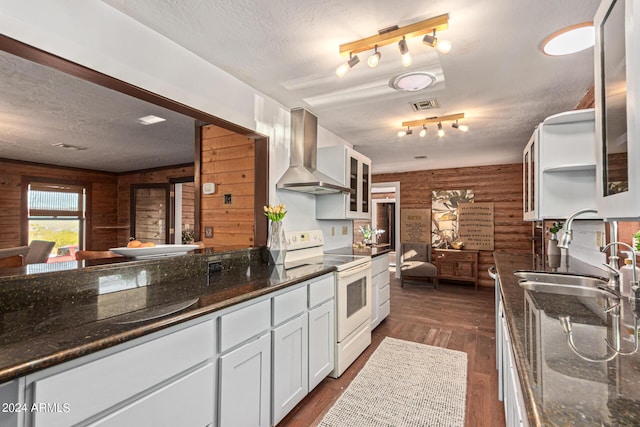 kitchen featuring wood walls, white range with electric cooktop, wall chimney range hood, dark hardwood / wood-style flooring, and white cabinetry