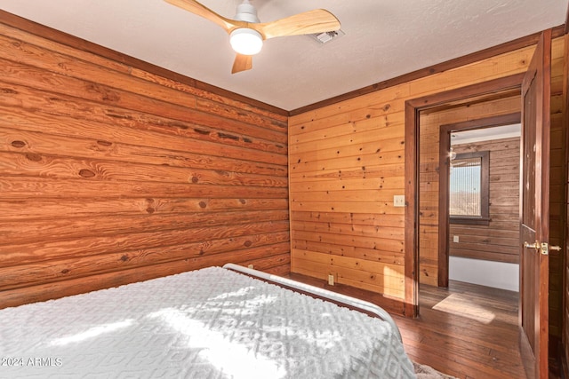 unfurnished bedroom with wood walls, ceiling fan, and dark wood-type flooring