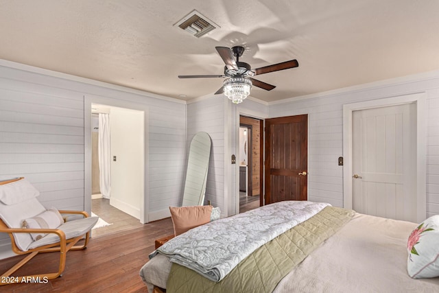 bedroom featuring ceiling fan, wooden walls, and wood-type flooring