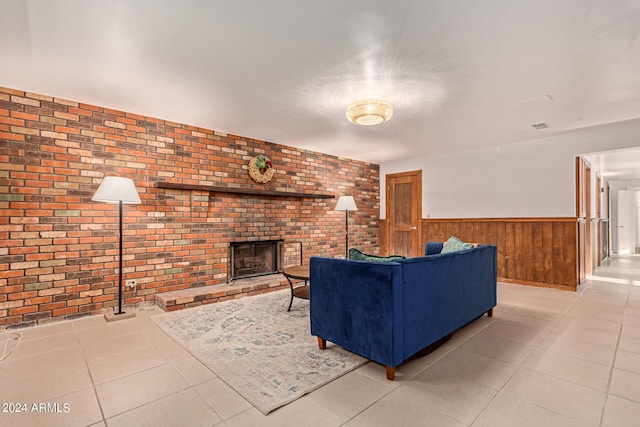 living room featuring light tile patterned floors, a brick fireplace, wooden walls, and brick wall