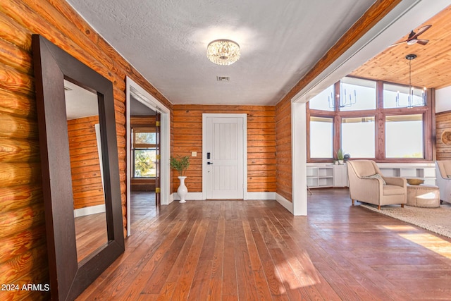 entryway with hardwood / wood-style flooring, wood walls, a textured ceiling, and a notable chandelier